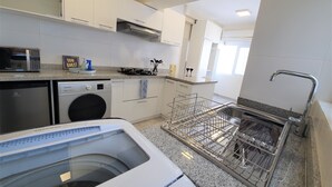 A modern kitchen with a dishwasher, washing machine, and a dish rack.
