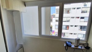 A room with a large window, a desk with a computer, and a wall socket.