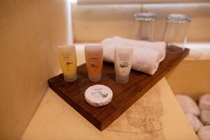 A wooden tray with four bottles of Regina spa therapy products and a round container with a green leaf design.