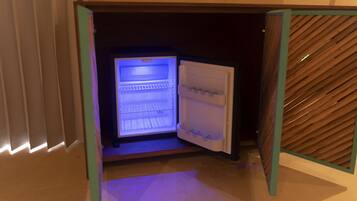 An open refrigerator with a blue interior light, a wooden panel on the right, and a tiled floor.