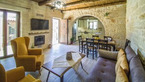 Un vaste espace de vie agrémenté d’un mur en pierre, d’un plafond en bois et d’un coin repas avec une table et des chaises.