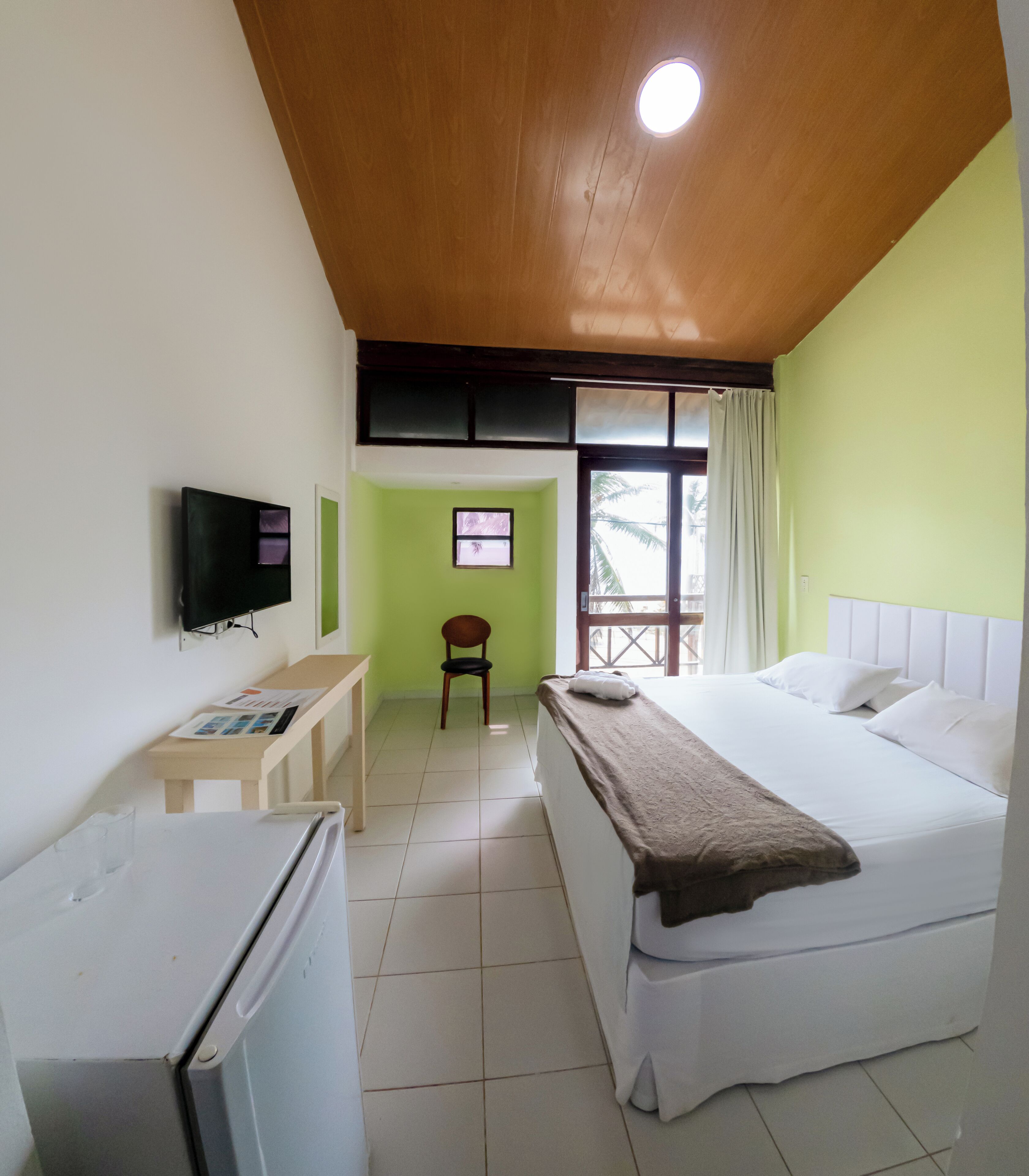 Ein Hotelzimmer mit Bett, Schreibtisch, Stuhl, Fernseher und Fenster.