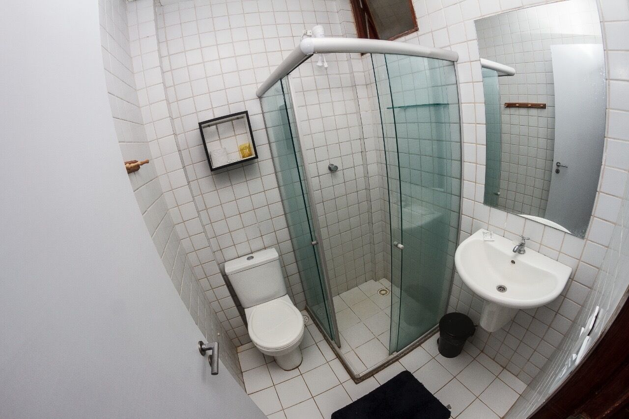 A bathroom with a glass-enclosed shower, a toilet, and a sink.