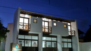 Un immeuble de deux étages doté de grandes fenêtres et d’un balcon.