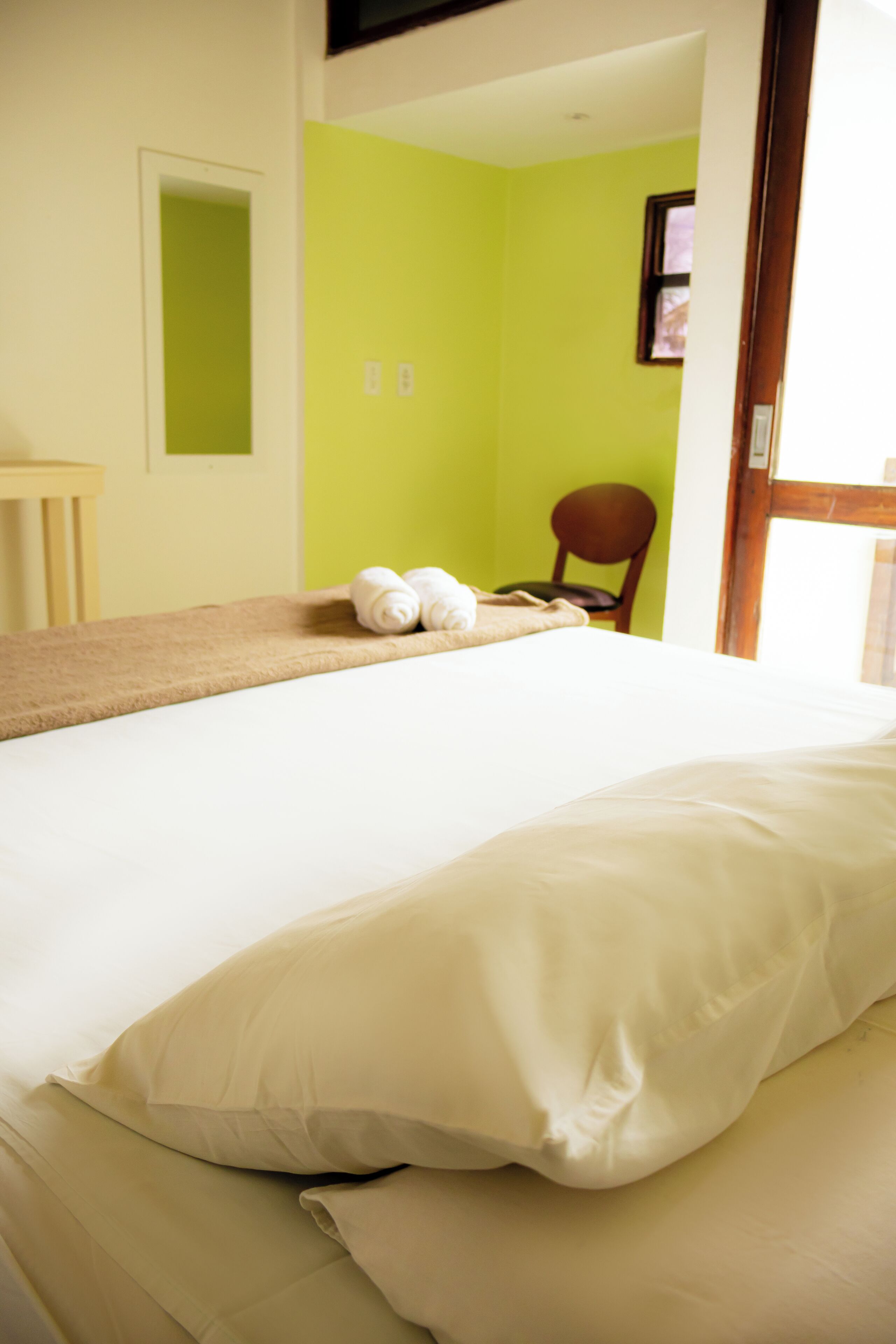Hotellihuone, jossa on sänky, tuoli ja pyyheteline.