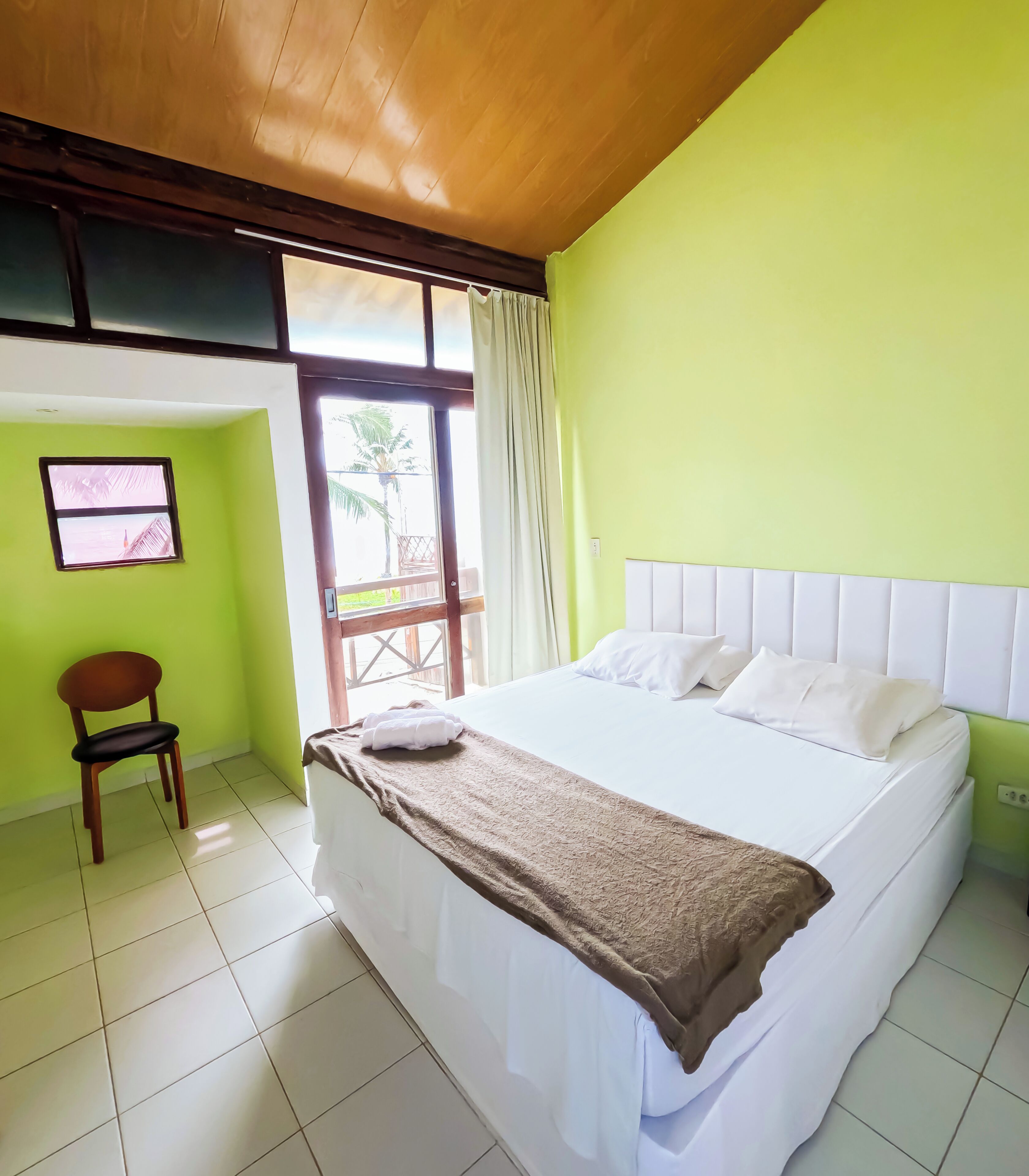 Una habitación con cama, una silla, una ventana y una puerta.