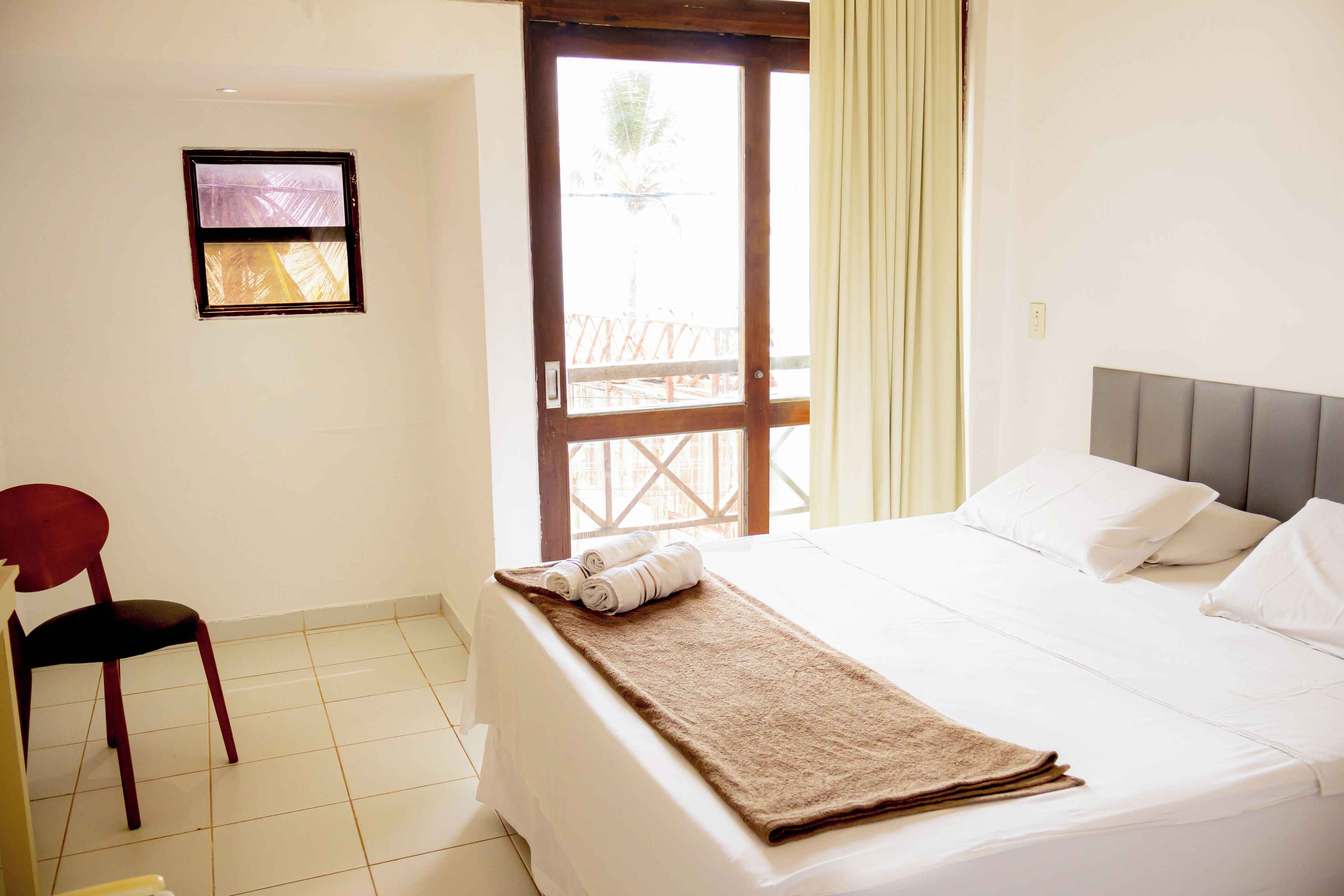 Habitación de hotel con cama, una silla, una ventana y vistas al exterior.