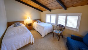 A bedroom with two beds, a chair, a nightstand, and a window with blinds. - Ocean Block. Steps from the beach! (Bethany Beach)