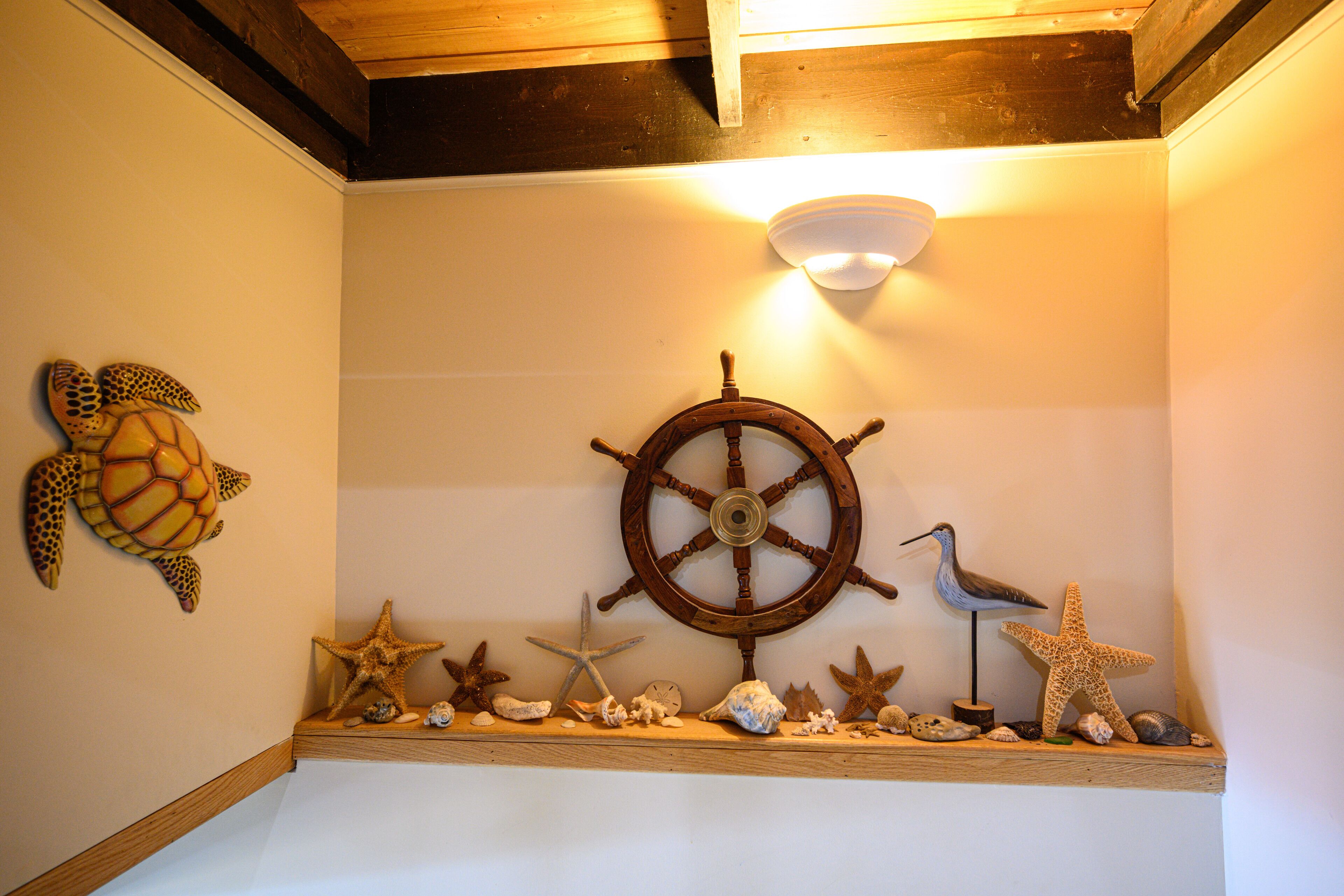 A shelf with various sea-themed decorations including a turtle, starfish, and a ship's wheel.