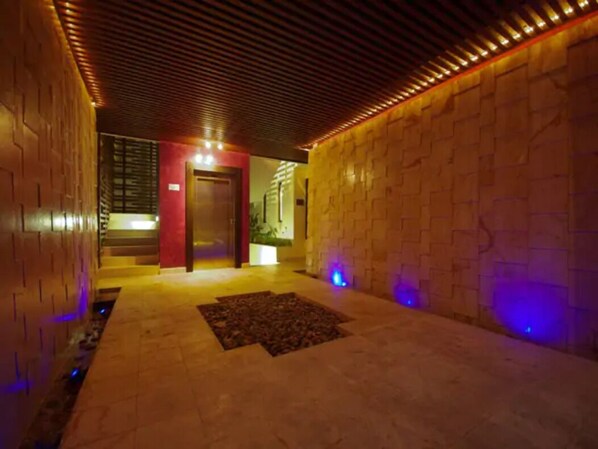 A hallway with a wooden ceiling and brick walls, leading to a door.