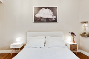 A bedroom with a large bed, two bedside tables with lamps, a nightstand, a framed picture on the wall, and a small statue on the nightstand. - GuestHost - Comfortable and modern 45sqm apartment that can accommodate up to 4 people. Located on the second floor, without a lift and with steps to access, of a typical Florentine building in the historic center alleys, the apartment is located few min (Firenze)
