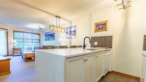 Une cuisine dotée d’un grand îlot central, de meubles en bois et d’une fenêtre avec des stores.