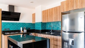 Een moderne keuken met een centraal eiland, roestvrijstalen apparatuur, houten keukenkastjes en turquoise backsplash tegels.