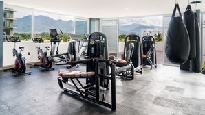 Een moderne sportschool met diverse trainingsapparaten, grote ramen met uitzicht op de bergen en een ruime indeling.