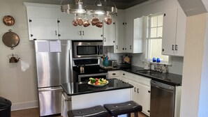 A modern kitchen with stainless steel appliances, white cabinets, and a central island with stools. - Picket Fence Cottage~ walk to MTSU and the historic downtown square!  (Murfreesboro)
