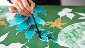 A hand holding a pen over a map with leaf patterns.