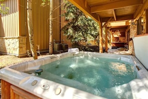 A hot tub in a covered outdoor area with a stone wall and wooden beams.