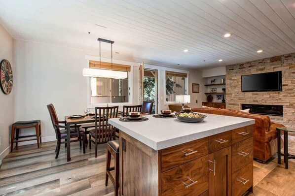 A modern kitchen with a central island, wooden cabinetry, and a stone accent wall.