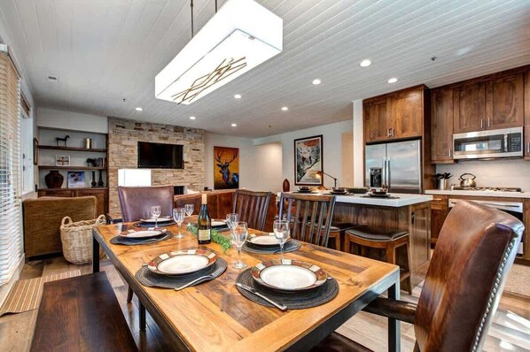 A modern kitchen with a built-in microwave, a large island, and a dining area set for six with a wooden table and six chairs.