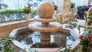 A multi-tiered stone fountain with water flowing into a reflective pool, surrounded by potted plants. - Weiluola Hotel Xiamen (Xiamen)