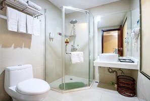 A modern bathroom with a glass-enclosed shower, a toilet, a sink with a mirror, and a towel rack.