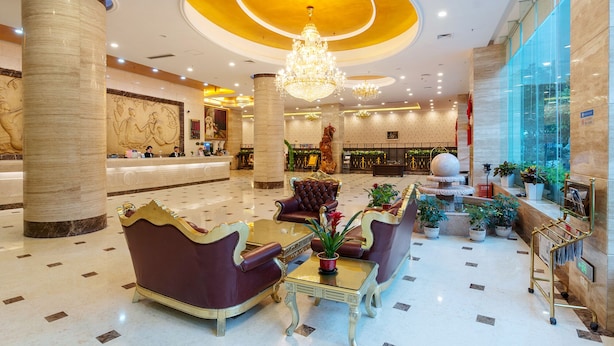 A spacious lobby with marble columns, a reception desk, and a chandelier. - Weiluola Hotel Xiamen (Xiamen)
