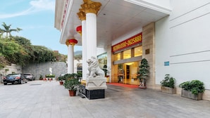 A hotel entrance with a red sign, a lion statue, and columns. - Weiluola Hotel Xiamen (Xiamen)