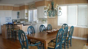 Una cocina con armarios de madera, una mesa de comedor con sillas y una araña.