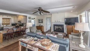 A spacious living area with a fireplace, a television, and a dining area with wooden chairs and a table. - Beach Blessing- Whole House (Edisto Island)
