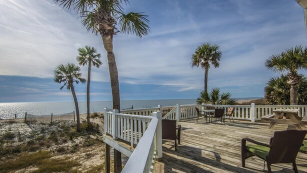 A wooden deck with outdoor seating, palm trees, and a view of the ocean. - Beach Blessing- Main (Edisto Island)