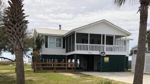 A two-story house with a balcony, a garage, and a fenced yard. - Beach Blessing- Main (Edisto Island)
