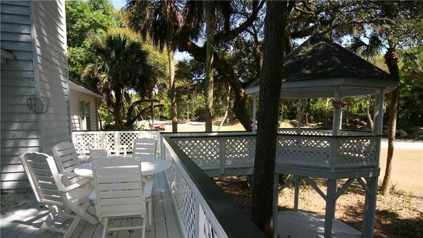 A covered outdoor deck with white furniture and a gazebo.