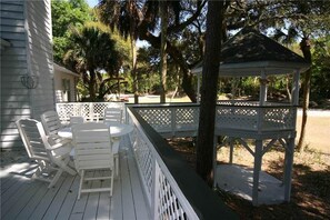 A covered outdoor deck with white furniture and a gazebo.