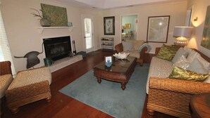 A living room with a fireplace, two sofas, a coffee table, and a ceiling fan.
