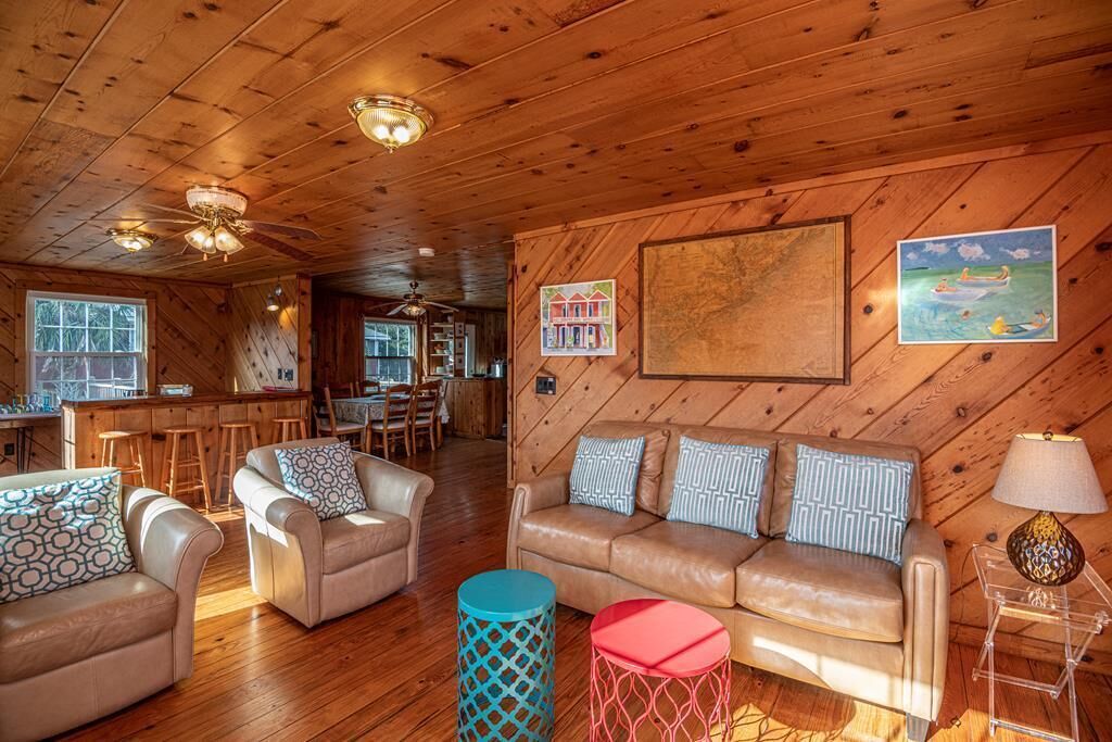 Interior acogedor de una cabaña con techo de madera, comedor, conjunto de sofás y una barra.