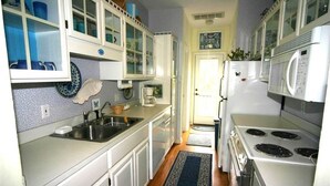 A kitchen with white cabinets, a sink, a stove, and a microwave. - Cupola House (Edisto Island)