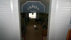 A narrow hallway leading to a living room with a sign reading "cuPola house". - Cupola House (Edisto Island)