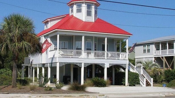A two-story house with a red roof and white exterior, featuring a balcony and a small tower-like structure on the roof. - Cupola House (Edisto Island)