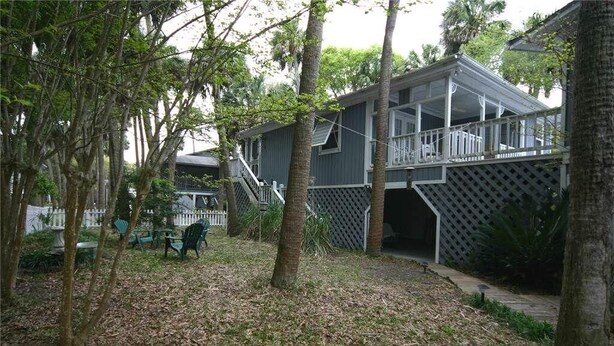A two-story house with a covered porch and a fenced yard.