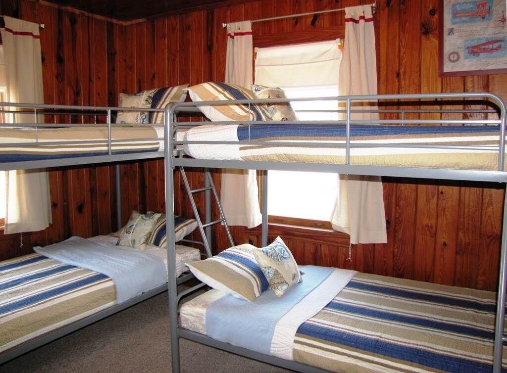 A bunk bed room with wooden walls, a ladder, and striped bedding.