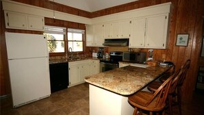 Una cocina con armarios de madera, encimera de granito y refrigerador.