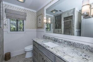 A bathroom with a white toilet, a marble sink, and a large mirror.
