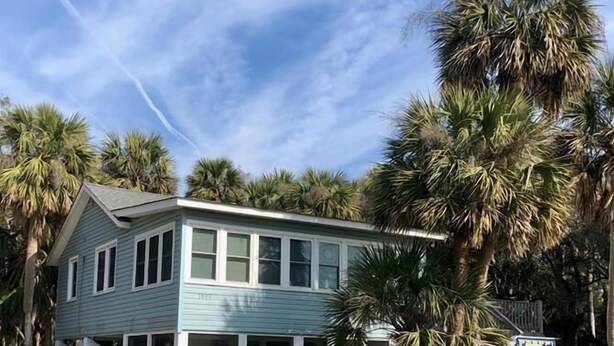 A two-story house with a covered porch and a fenced yard. - Rich Tymes (Edisto Island)