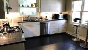 A modern kitchen with white cabinets, a gas stove, a dishwasher, and a microwave. - Seaczar's Retreat (Edisto Island)