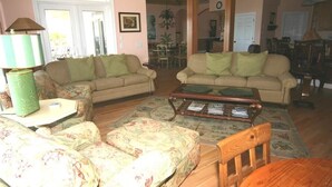 A living room with two sofas, a coffee table, and a dining area visible in the background.
