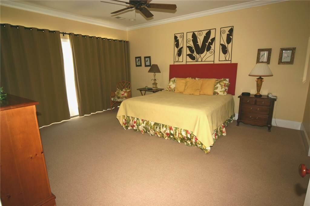 A bedroom with a bed, a nightstand, a lamp, a dresser, and a ceiling fan.