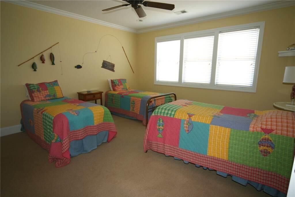 Ein Schlafzimmer mit zwei Betten, einem Deckenventilator, einem Fenster mit Jalousien und Wanddekorationen.