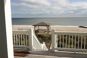 A beach view from a wooden deck with a gazebo in the middle.