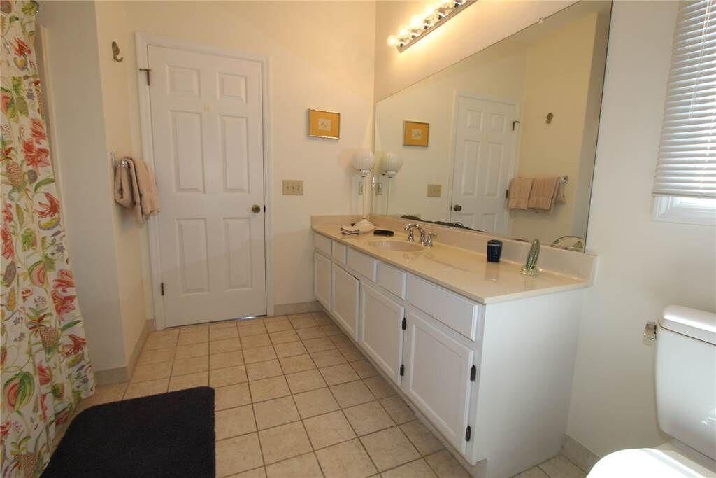 A bathroom with a white door, a sink with a mirror, and a toilet.