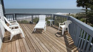 A wooden deck with white lounge chairs and a small table, overlooking the ocean. - The Point (Edisto Island)